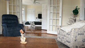 Ein geräumiges Wohnzimmer mit einem dunkelblauen Sessel, einem gemusterten Sofa und einem Holztisch.