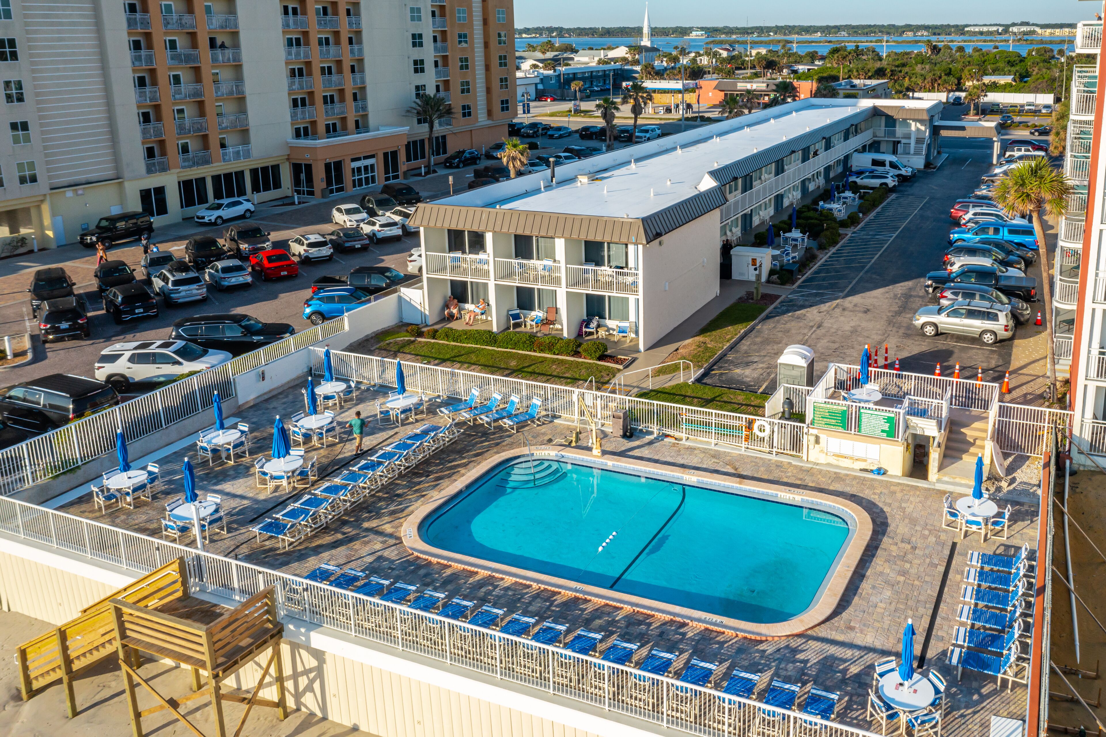 A hotel with a rooftop pool, multiple parking lots, and a view of the surrounding cityscape.