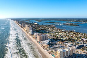 Vista aérea de una ciudad costera con playa, zona urbana densa y puerto deportivo.