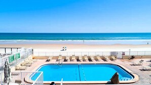 Ein Pool mit Liegestühlen und Blick auf den Strand.