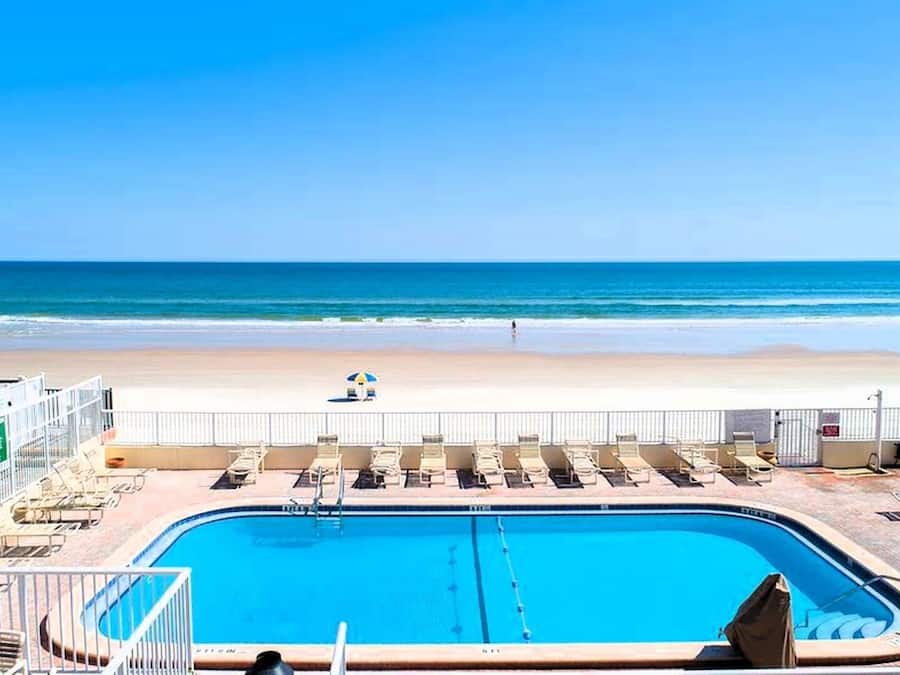 Une piscine avec des chaises longues et vue sur la plage.