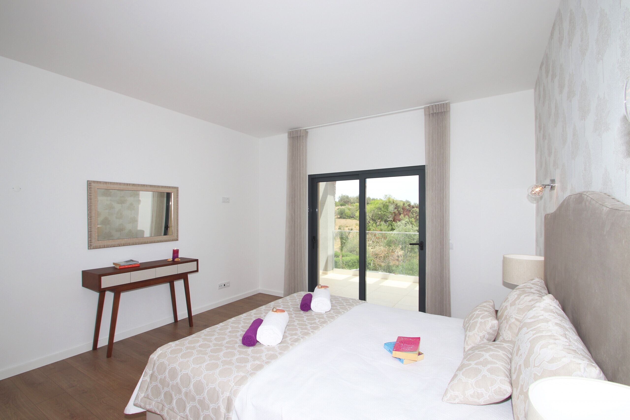 Ein Hotelzimmer mit Bett, Nachttisch, Spiegel und Blick ins Freie.