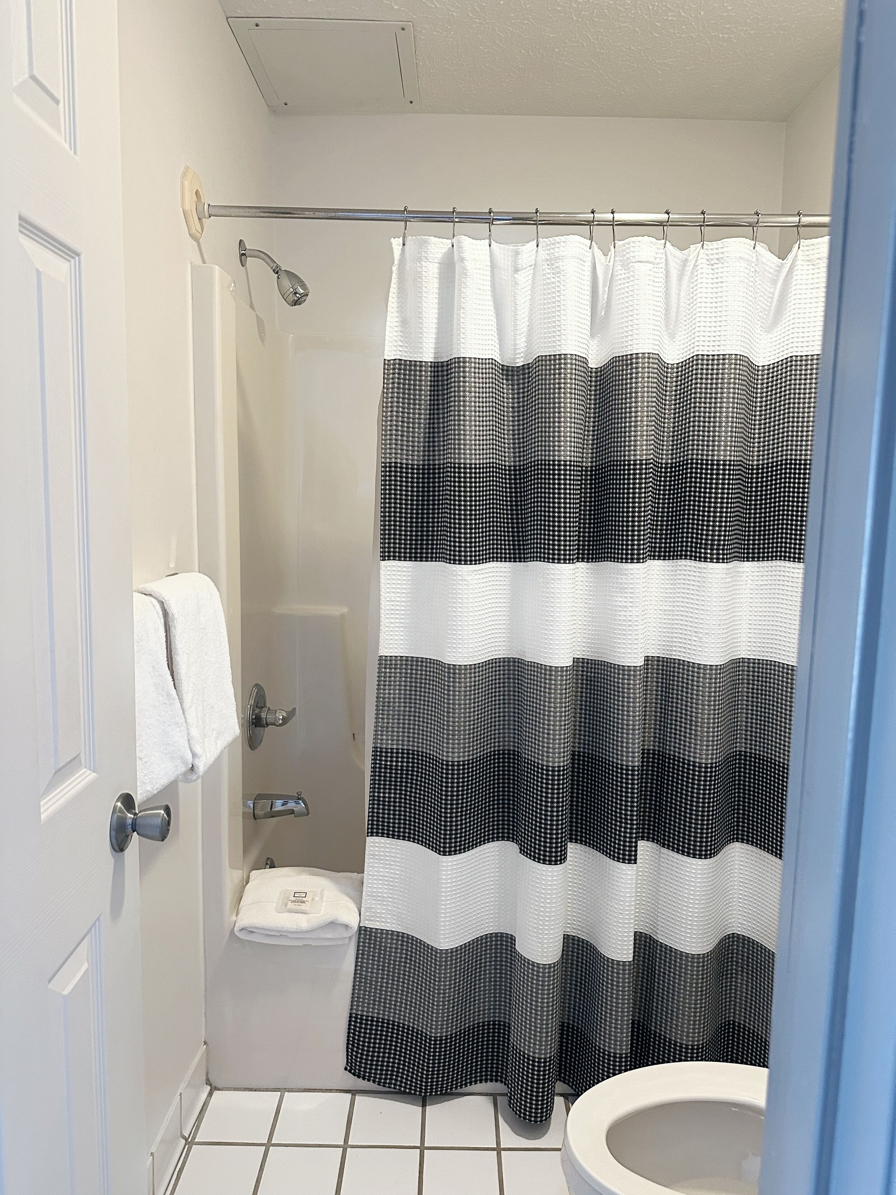 A bathroom with a shower curtain, a toilet, and a towel rack.
