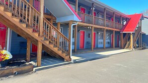 A motel with multiple balconies, wooden staircases, and a red roof. - Baja Motel (Oakland)