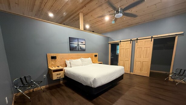A bedroom with a wooden ceiling, a bed, a nightstand, a chair, and a wardrobe. - Baja Motel (Oakland)