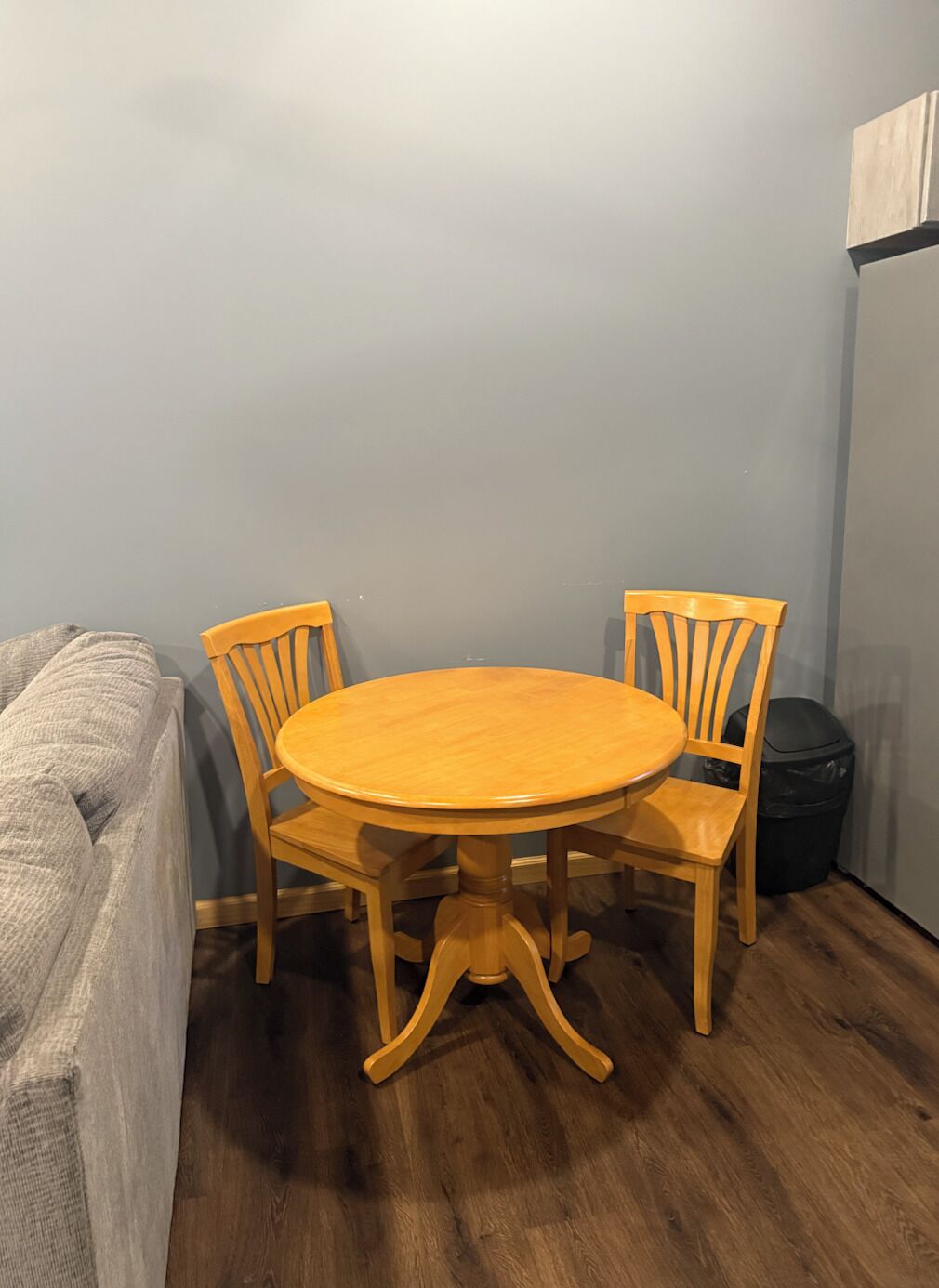 Un pequeño comedor con una mesa redonda de madera y cuatro sillas a juego.