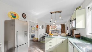 A modern kitchen with a stainless steel refrigerator, a built-in oven, and a microwave. There is a window providing natural light and a view of the outside. - Pops Place - Omarama Holiday Home (Omarama)