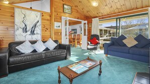 A cozy living room with a wooden ceiling, two sofas, a coffee table, and a large painting.