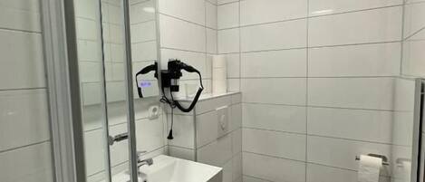 Un baño moderno con cabina de ducha de vidrio, un lavabo blanco y un inodoro.