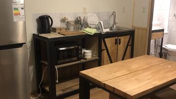 Una cocina funcional con un refrigerador de acero inoxidable, una mesa de madera y un lavamanos.