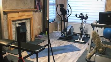 Une salle de sport à domicile équipée d’un tapis de course, d’un vélo d’appartement, d’un banc de musculation et de divers poids.