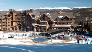 Ein großes Chalet mit mehreren Stockwerken und einem Skiliftbereich im Vordergrund.