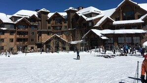 Ein schneebedecktes Skigebiet mit Berghütern, Skipisten und Skifahrern.
