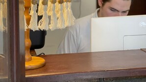 A person working at a desk with a lamp and a computer. - Peixe Crew Rua das Pedras (Búzios)