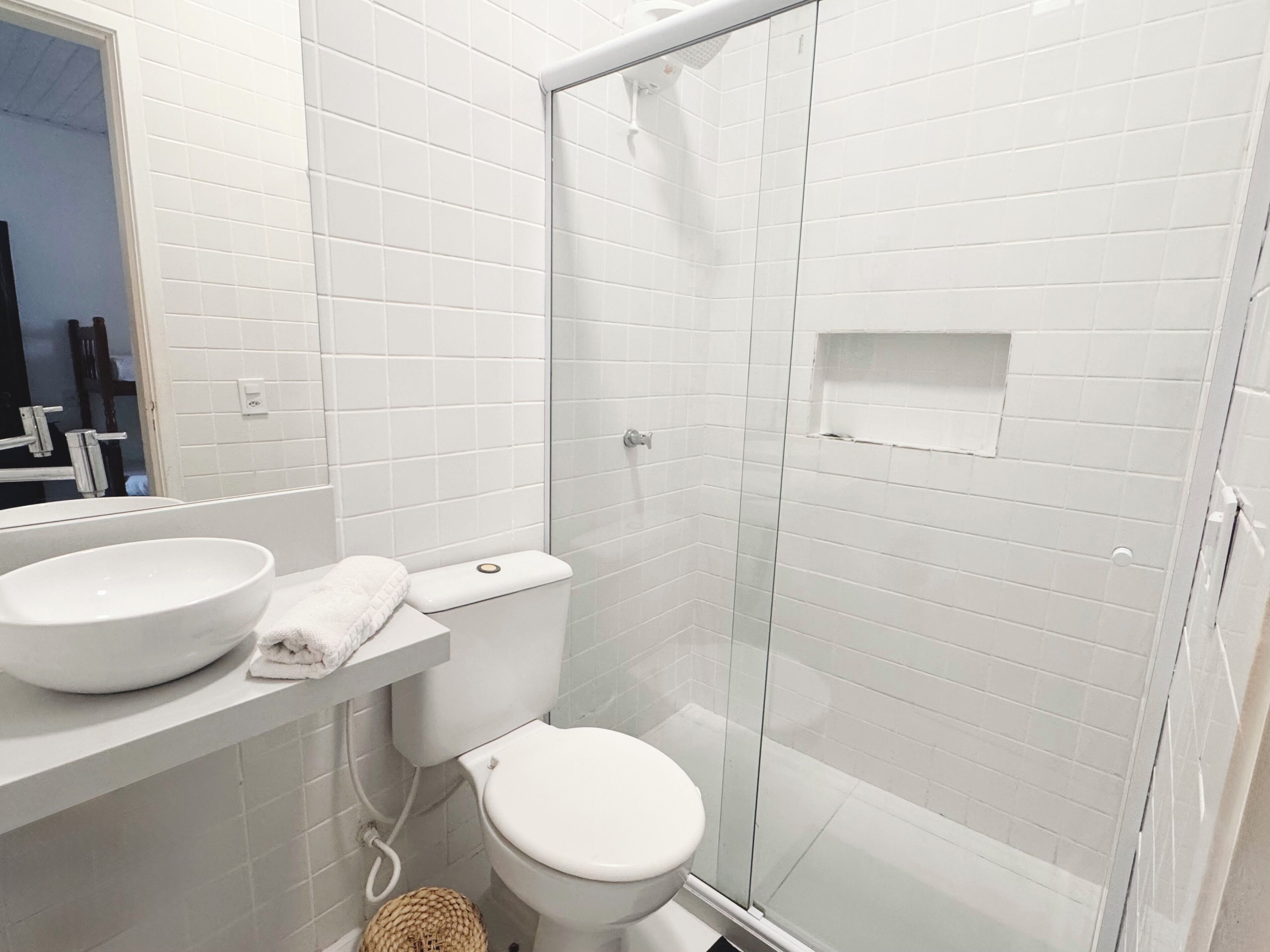 A bathroom with a white sink, toilet, and glass shower enclosure.