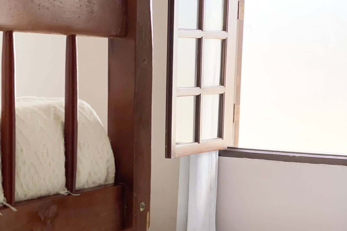 Een houten hemelbed met een witte matras en opgevouwen witte handdoeken.