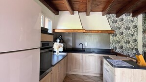 Una cocina con armarios de madera, encimera negra y suelo de baldosas.