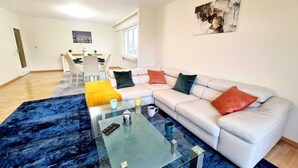 A modern living room with a sectional sofa, a glass coffee table, and a blue patterned rug. - New 2bedrooms in Center Terrace&Parking (Luxembourg City)