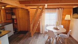 En hyggelig træhytte med tekøkken, spiseplads og trappe.
