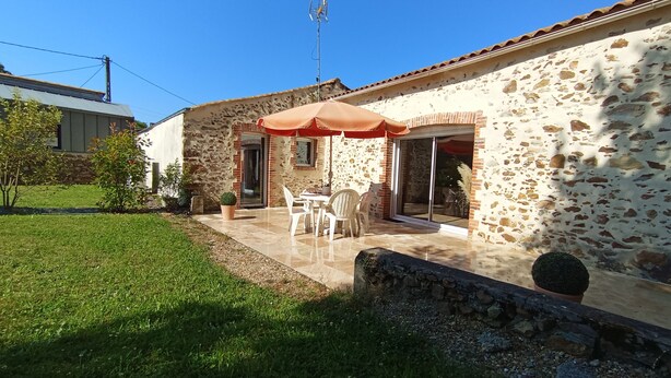 A stone house with a patio, outdoor seating, and a large umbrella.