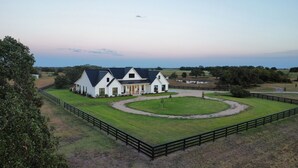 A large white farmhouse with a black roof, surrounded by a fenced property and a circular driveway. - RMB Longhorn West, luxury living in the country (Weimar)