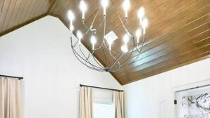 A bedroom with a wooden ceiling, a large bed with a green bench, a chandelier, and a door with a marble design. - RMB Longhorn West, luxury living in the country (Weimar)