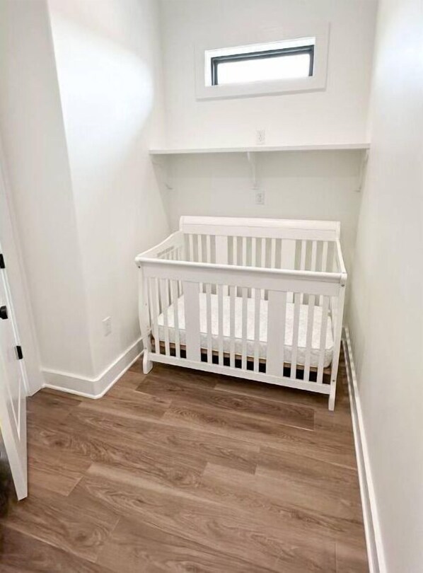 A white crib in a corner of a room with wooden flooring and white walls. - RMB Longhorn West, luxury living in the country (Weimar)