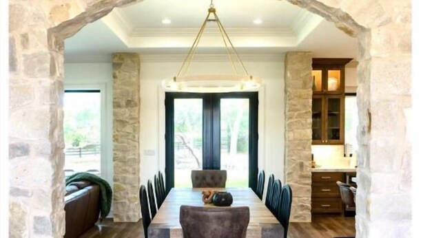 A dining area with a stone archway, a wooden dining table, and chairs. - RMB Longhorn West, luxury living in the country (Weimar)