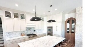 A modern kitchen with a marble island, wooden bar stools, and pendant lighting. - RMB Longhorn West, luxury living in the country (Weimar)
