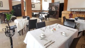 Een restaurant met meerdere tafels klaar voor diners, met een centrale grill en plafondventilatoren.