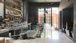 Cozinha moderna com ilha de mármore, área de bar com prateleiras de garrafas e uma grande janela que oferece luz natural.