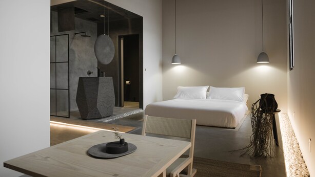 Quarto de hotel moderno com cama, mesa de jantar e uma escultura única.