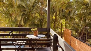 A covered outdoor seating area with a table and chairs, surrounded by lush greenery. - Brand New Studio with Sunset View (Haleiwa)
