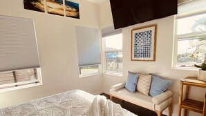 A bedroom with a large bed, a sofa, a TV, and a window with a view. - Brand New Studio with Sunset View (Haleiwa)