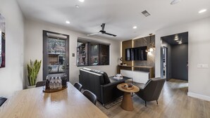 Un salon moderne avec une grande table à manger en bois, un canapé et un téléviseur fixé au mur.