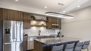 A modern kitchen with a stainless steel refrigerator, a microwave, and a large island with bar stools.