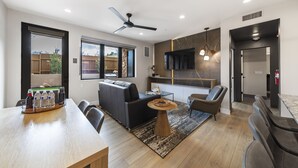 A modern living room with a sofa, chairs, a coffee table, and a TV mounted on the wall.