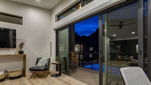 A modern living room with a large sliding glass door leading to a pool area. - LaFave-Luxury Villa at Zion: Johnson Mountain (Springdale)