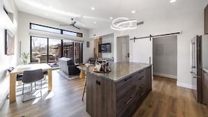 A modern kitchen with a large island, wooden cabinets, and a built-in oven.