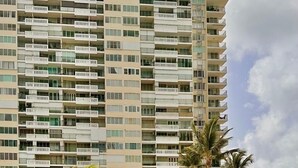 A hotel with a swimming pool, palm trees, and a multi-story building with balconies. - Relax in this comfortable apartment with Oceanview on the 21st floor (Luquillo)