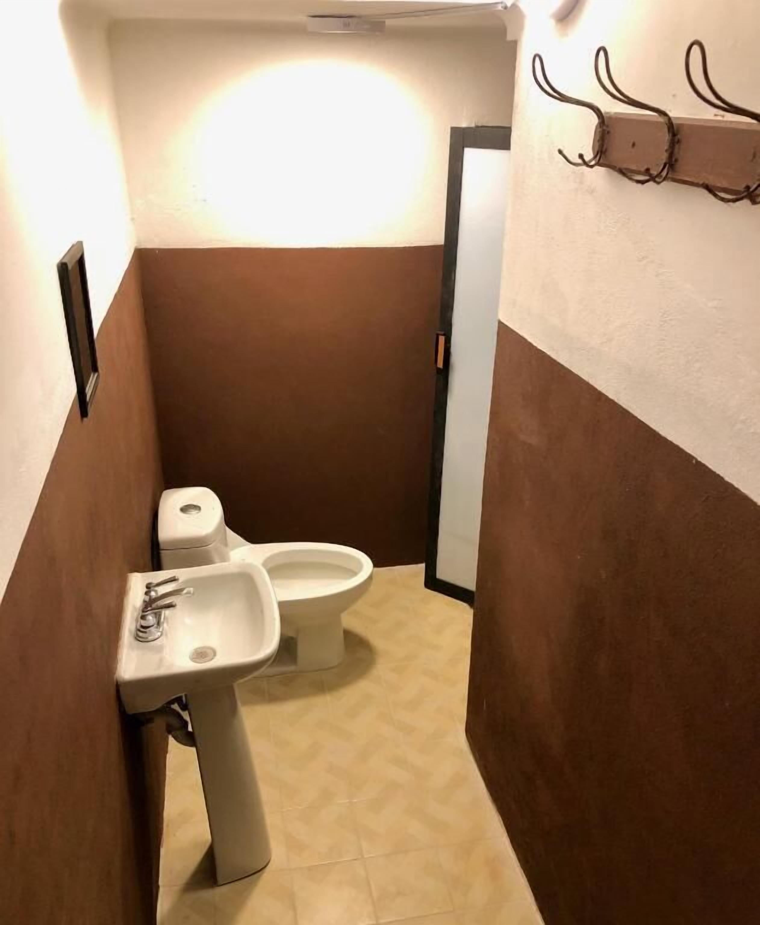 Un baño estrecho con inodoro, lavamanos y un toallero en la pared.