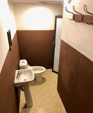 Un baño estrecho con inodoro, lavamanos y un toallero en la pared.
