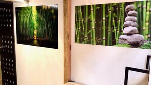 A room with a bed, a desk, and two chairs. There are two wall-mounted pictures, one of a forest path and another of stacked stones. - ROOMIES HOSTEL - Calle Puebla (Mexico City)