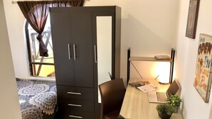 A bedroom with a bed, a desk with a laptop, a chair, and a wardrobe. - ROOMIES HOSTEL - Calle Puebla (Mexico City)