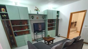 Un saló amb un sofà, televisió i prestatges decorats amb objectes ornamentals.