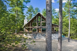 A cabin with a stone foundation, wooden exterior, and a porch with steps leading to the entrance.