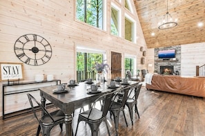 A spacious dining area with a long table, multiple chairs, and a clock on the wall.