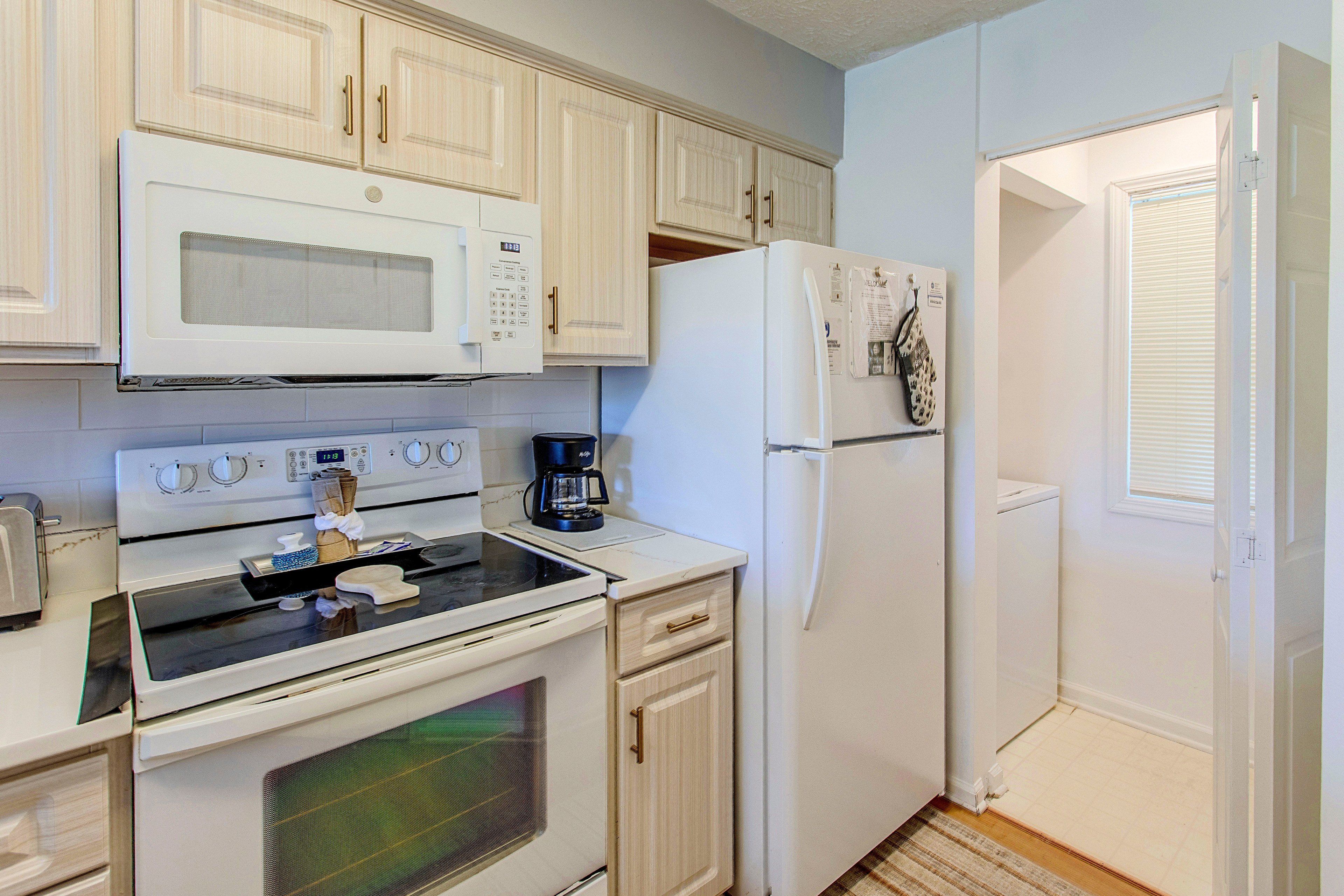 A kitchen with white appliances, including a microwave, stove, and refrigerator.