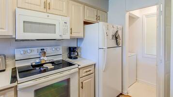 A kitchen with white appliances, including a microwave, stove, and refrigerator.