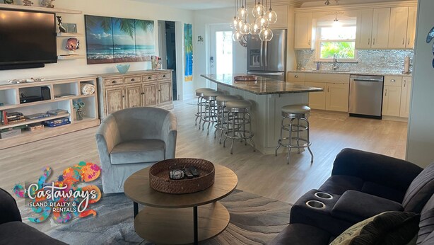 A modern kitchen with a central island, bar stools, and a dining area.